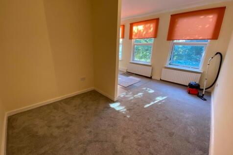 A bright double bedroom featuring three large w...