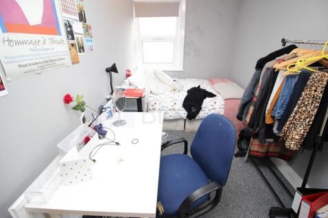 A cozy single bedroom featuring a study desk wi...