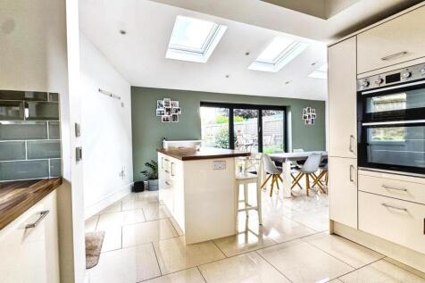 A bright, modern kitchen featuring skylights an...