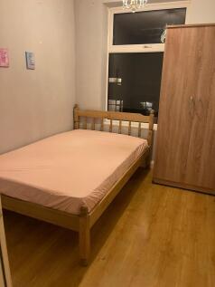 Cozy single bedroom featuring a wooden bed fram...