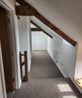 A bright and tidy hallway featuring exposed woo...