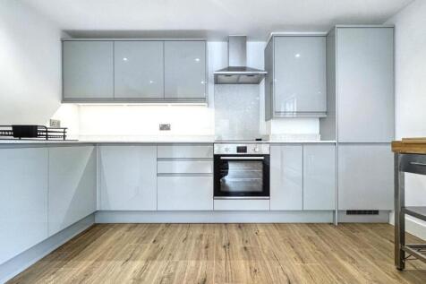 A modern, spotless kitchen featuring sleek grey...