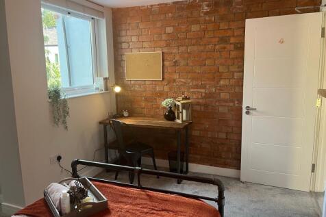 A cozy single bedroom featuring a stylish expos...