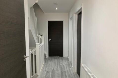 A clean, modern hallway with light grey wood fl...