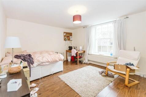 A spacious and bright bedroom featuring a comfo...
