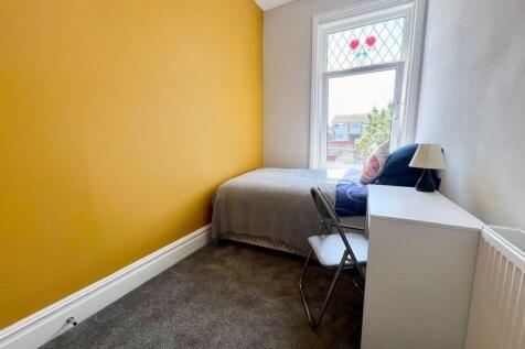 A cozy single bedroom featuring a bright yellow...