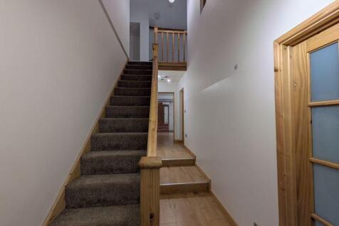 A bright and clean hallway featuring wooden ban...