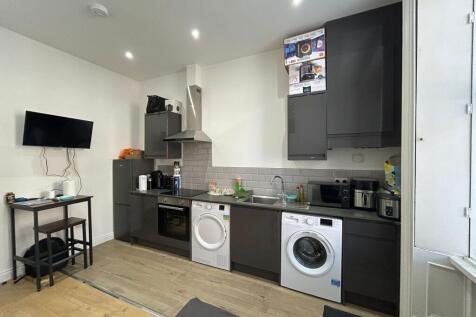 Modern kitchen area with sleek black cabinetry,...