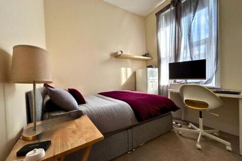 A cozy, well-lit single bedroom featuring a com...