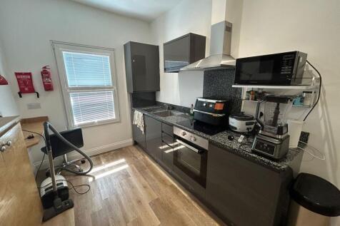 A sleek modern kitchen featuring dark cabinetry...