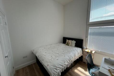 A bright, clean single bedroom with natural lig...