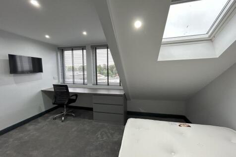 A spacious and modern bedroom featuring a large...