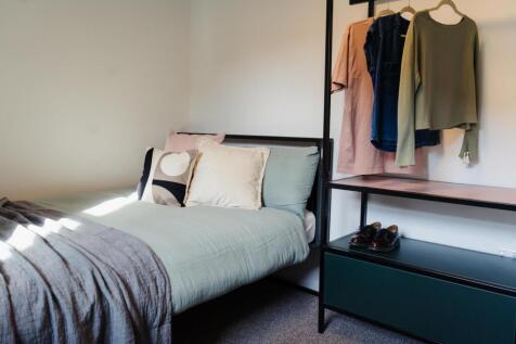 A cozy single bedroom featuring a neatly made b...