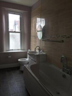 A clean and well-lit bathroom featuring a bath ...