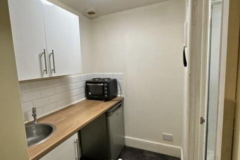 Compact kitchen with modern white cabinetry, wo...