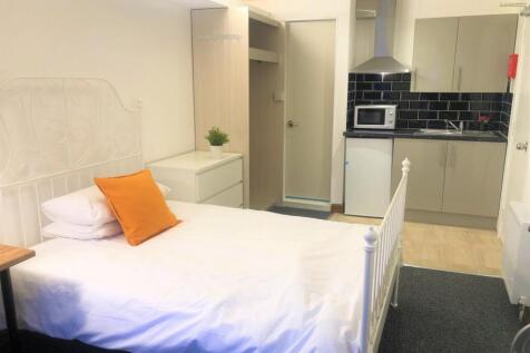 A clean and cozy single bedroom featuring a whi...