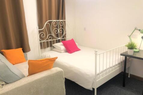 A cozy single bedroom featuring a decorative wh...