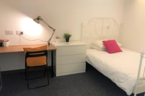 A cozy single bedroom featuring a neat white me...