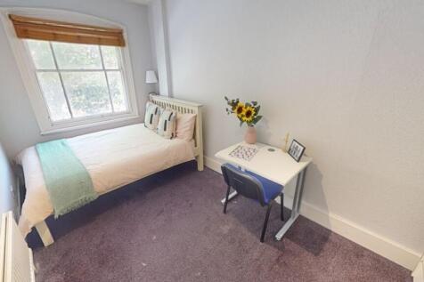 A cozy single bedroom featuring a comfortable b...