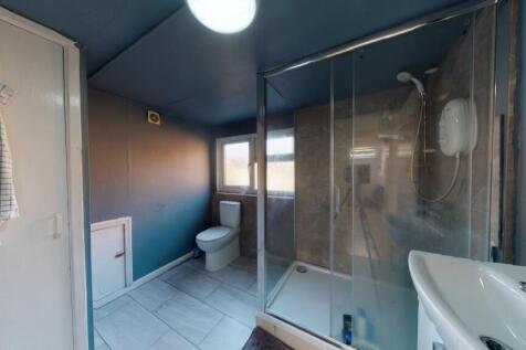 A modern bathroom featuring a spacious glass sh...