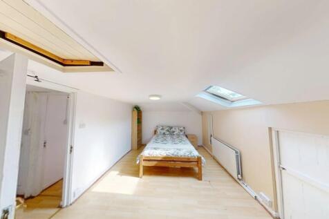 A bright attic bedroom with a sloped ceiling an...