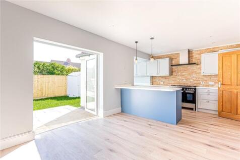 A bright and modern kitchen featuring light woo...
