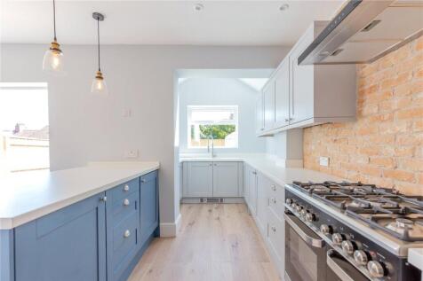 A modern kitchen featuring blue cabinetry, a sl...