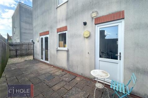 A spacious paved garden area with a small seati...