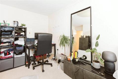 A compact, tidy single bedroom featuring a desk...