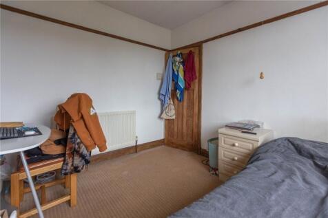 A modest single bedroom featuring a simple desk...