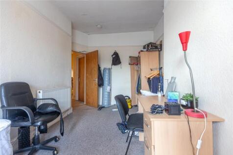 A functional single bedroom featuring a desk an...
