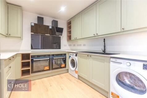 A modern kitchen featuring light wood flooring,...