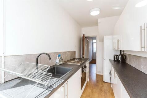 A modern, clean galley kitchen featuring white ...