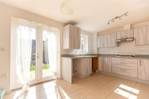 A bright and modern kitchen featuring large gla...