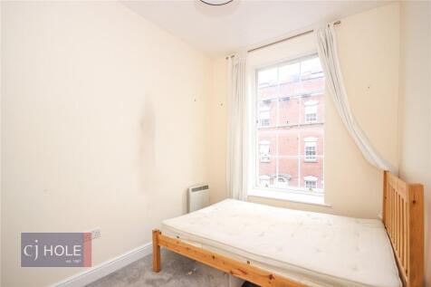Bright single bedroom featuring a large window ...