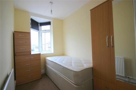 A bright, compact bedroom featuring a large win...