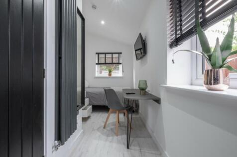 A cozy double bedroom featuring a stylish desk ...