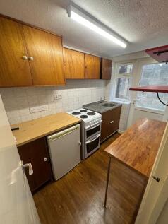 A compact kitchen featuring wooden cabinets, ti...