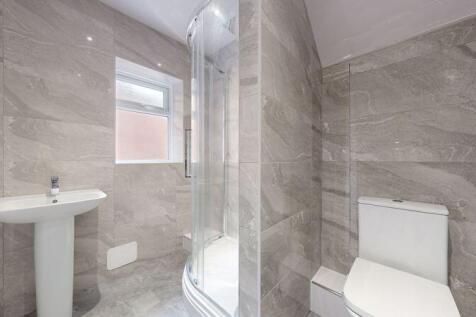 A modern bathroom suite featuring a glass-enclo...