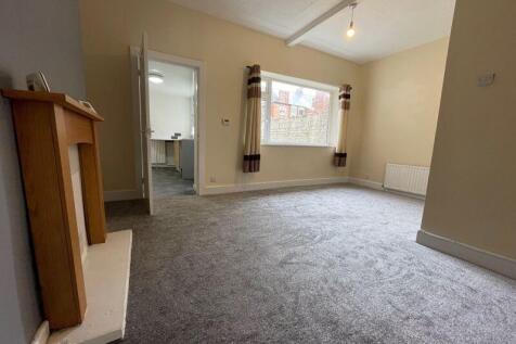 A spacious and well-lit living room featuring a...