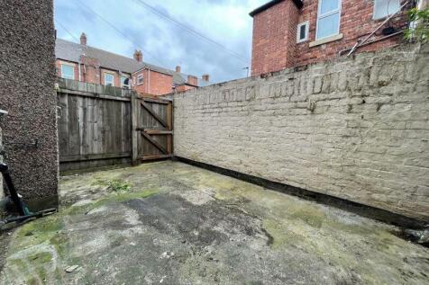 A private, enclosed garden area with a paved gr...