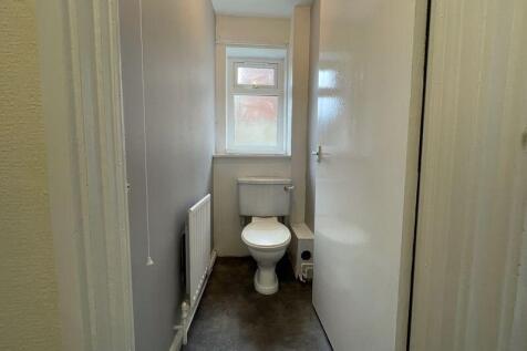A compact and clean single toilet room featurin...