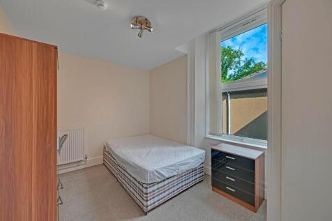 A neat and tidy single bedroom featuring a comf...