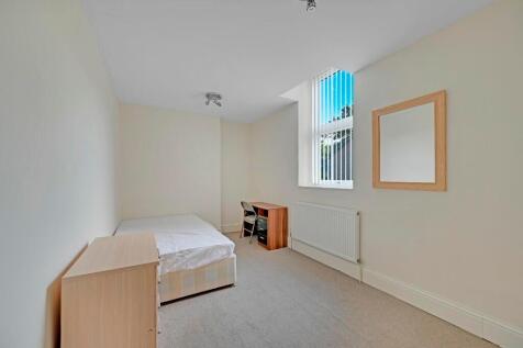 A neat and well-lit single bedroom with a simpl...