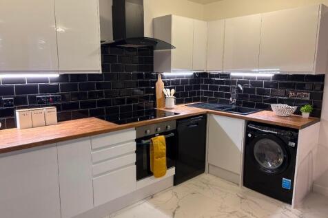 Modern kitchen with sleek white cabinets, wood-...