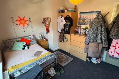 A cozy single bedroom with a neatly made bed, a...