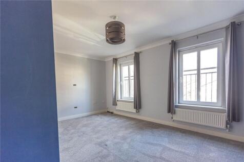 A bright double bedroom featuring two large win...