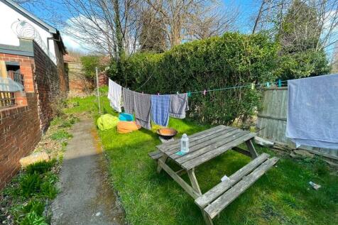 A sunny garden area featuring a wooden picnic b...