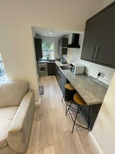 A modern, compact kitchen featuring a sleek cou...