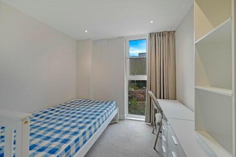 A neat and tidy single bedroom featuring a comf...